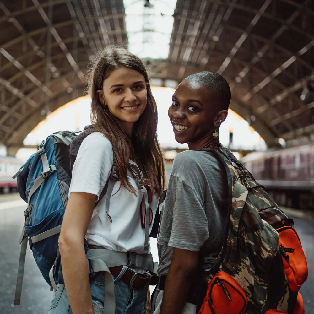Two travelers smiling at a train station